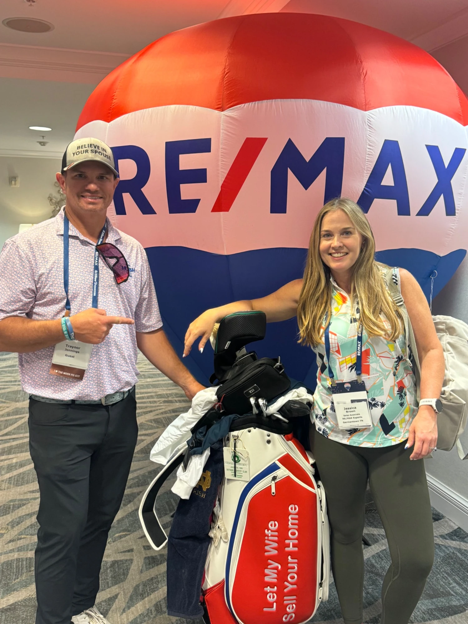 Jessica Brown and Traynor Jennings at a RE/MAX golf event with a Let My Wife Sell Your Home golf bag