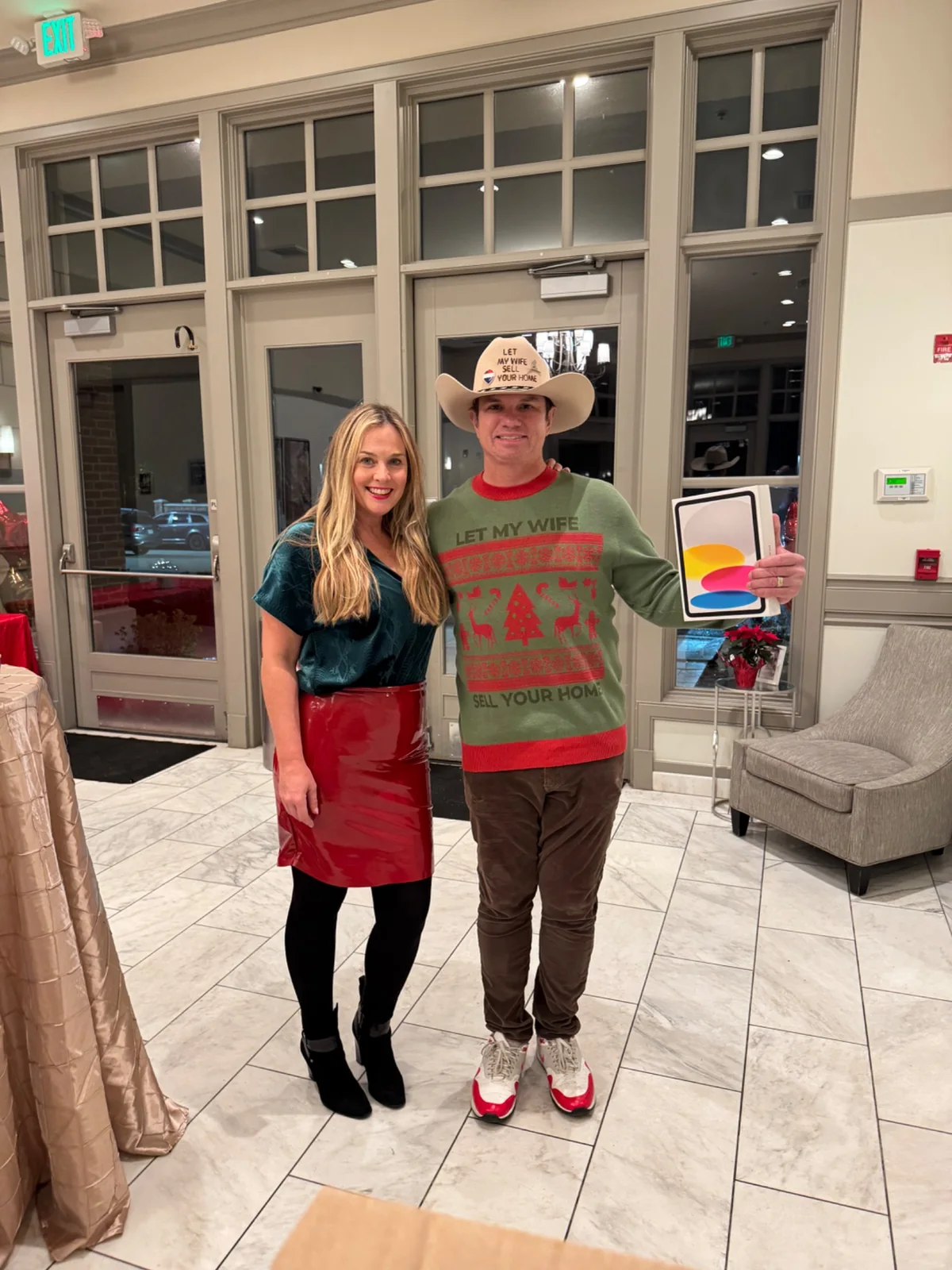 Jessica and Traynor together at a holiday event wearing Let My Wife Sell Your Home branding